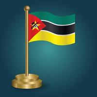 Mozambique national flag on golden pole on gradation isolated dark background. table flag, vector illustration