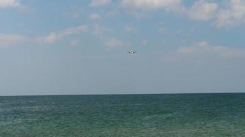 The plane descends over the ocean before landing, slow motion. Travel by sea video