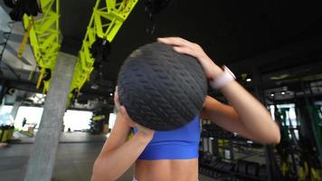 Woman at gym uses weighted ball in exercise video