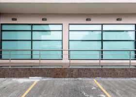 Front view of an office building with square glass windows and ground parking. photo