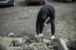 Guy picks up rock Man in black jacket. photo