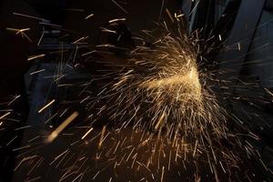 Sparks from saw. Lots of sparks in dark. Sawing steel. photo
