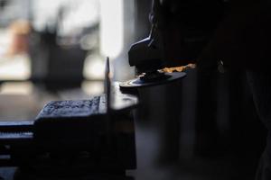 Grinding steel. Worker grinds metal. Work in garage. Electric tool in hand. photo