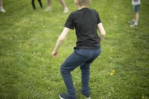 Child on green grass. Schoolboy plays on lawn in summer. Active holidays. photo