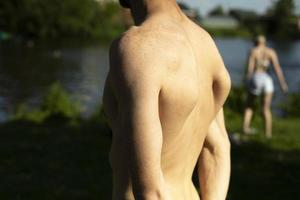 el chico está de vuelta en verano. la espalda desnuda del hombre en un día caluroso. hombre de mediana edad en la playa. foto