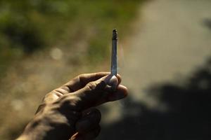 Cigarette in hand. Self-rolling with tobacco. photo