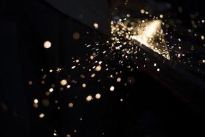 Sparks from grinding. Metal work. Steel profile cutting parts. Lights in dark. photo