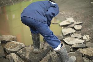 Worker lifts rocks. Repair of road. Construction waste. photo