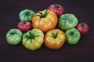 Picked multicolored homegrown tomatoes, red yellow green orange colors on dark table photo