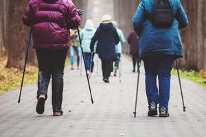 Group of women walking in the city park, pole-walking in autumn photo