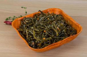 Laminaria salad in a bowl on wooden background photo