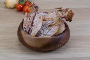 Dried squid in a bowl on wooden background photo