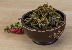 Laminaria salad in a bowl on wooden background photo