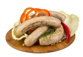 Grilled sausages on wooden board and white background photo