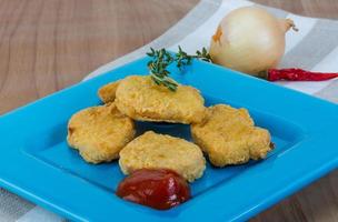 Nuggets on the plate and wooden background photo