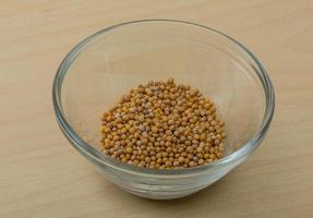 Mustard seeds in a bowl on wooden background photo