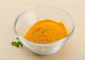 Tumeric powder in a bowl on wooden background photo