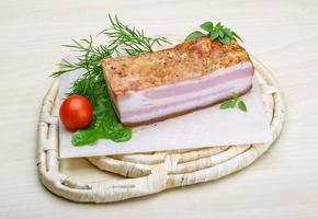 Raw bacon on wooden board and wooden background photo