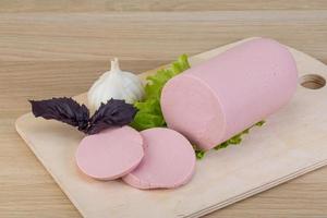 Sausage on wooden board and wooden background photo