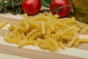 Raw rotini on wooden board and wooden background photo