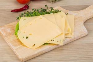 Sliced cheddar on wooden board and wooden background photo