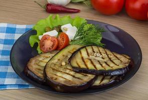 berenjena a la parrilla en el plato y fondo de madera foto