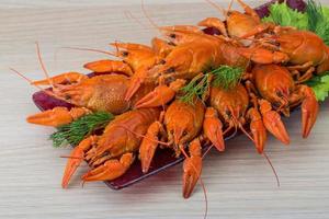 Boiled crayfish on the plate and wooden background photo