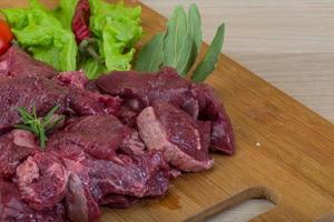 Raw venison on wooden board and wooden background photo