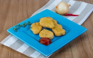 Nuggets on the plate and wooden background photo