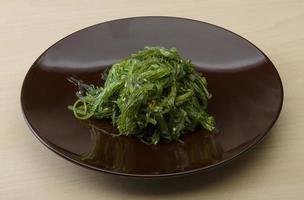 Chuka salad on the plate and wooden background photo