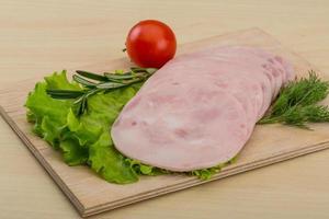 Sliced ham on wooden board and wooden background photo