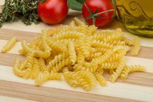 Raw rotini on wooden board and wooden background photo