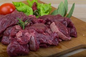 Raw venison on wooden board and wooden background photo