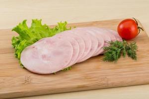 Sliced ham on wooden board and wooden background photo