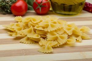 Raw farfalle on wooden background photo