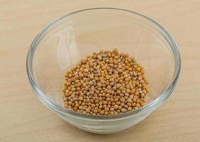 Mustard seeds in a bowl on wooden background photo