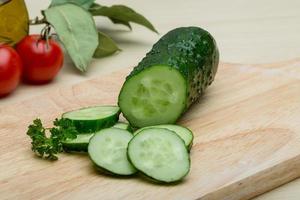 pepino en rodajas sobre tablero de madera y fondo de madera foto