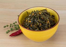 Laminaria salad in a bowl on wooden background photo