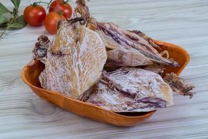 Dried squid in a bowl on wooden background photo