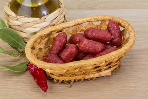 Mini salami in a basket on wooden background photo