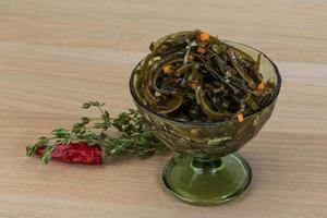 Laminaria salad in a bowl on wooden background photo