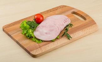 Sliced ham on wooden board and wooden background photo