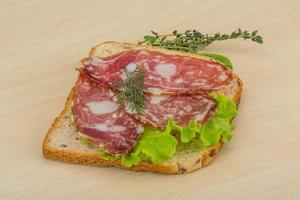 Salami sandwich on wooden background photo