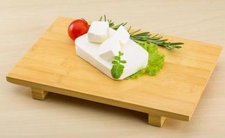 Feta cheese on wooden board and wooden background photo