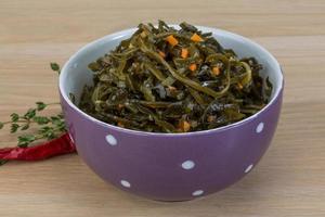 Laminaria salad in a bowl on wooden background photo