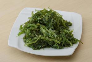 Chuka salad on the plate and wooden background photo