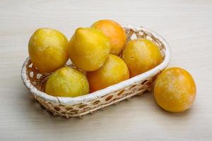 Yellow plums in a basket on wooden background photo