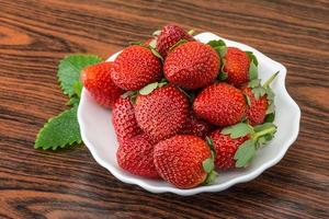 Fresh strawberry in a bowl on wooden background photo