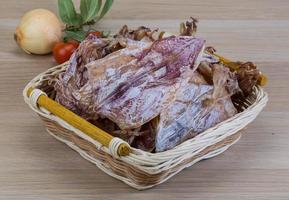 Dried squid in a basket on wooden background photo