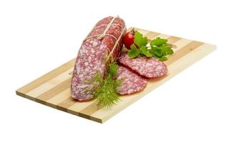 Salami on wooden board and white background photo